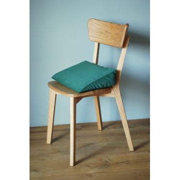 Poduszka klinowa w kolorze zielonym na krześle w jasnym wnętrzu.