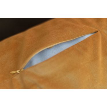 Zbliżenie na metkę poduszki w kolorze różowym z napisem „Made to support your body & mind” na tle kolorowego, orientalnego dywanu.