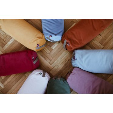 Kolorowe wałki do jogi WELLB ułożone w okrąg na drewnianej podłodze; widoczne odcienie czerwieni, zieleni, błękitu, pomarańczu, różu, żółci i beżu, z metkami marki.