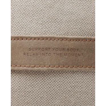 Zbliżenie na uchwyt z celulozowej skóry na małym wałku gryczanym WellB z wytłoczonym napisem „Support your body. Relax into the moment”.